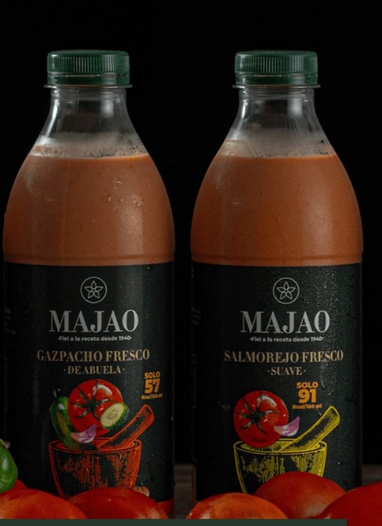 Botellas de gazpacho fresco de abuela Majao junto a ingredientes frescos.